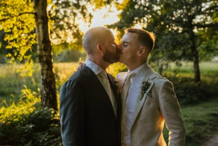 same sex wedding couple kissing in a field at golden hour